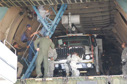 People loading truck into plane