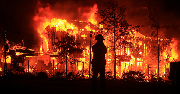 firefighter standing in front of fire